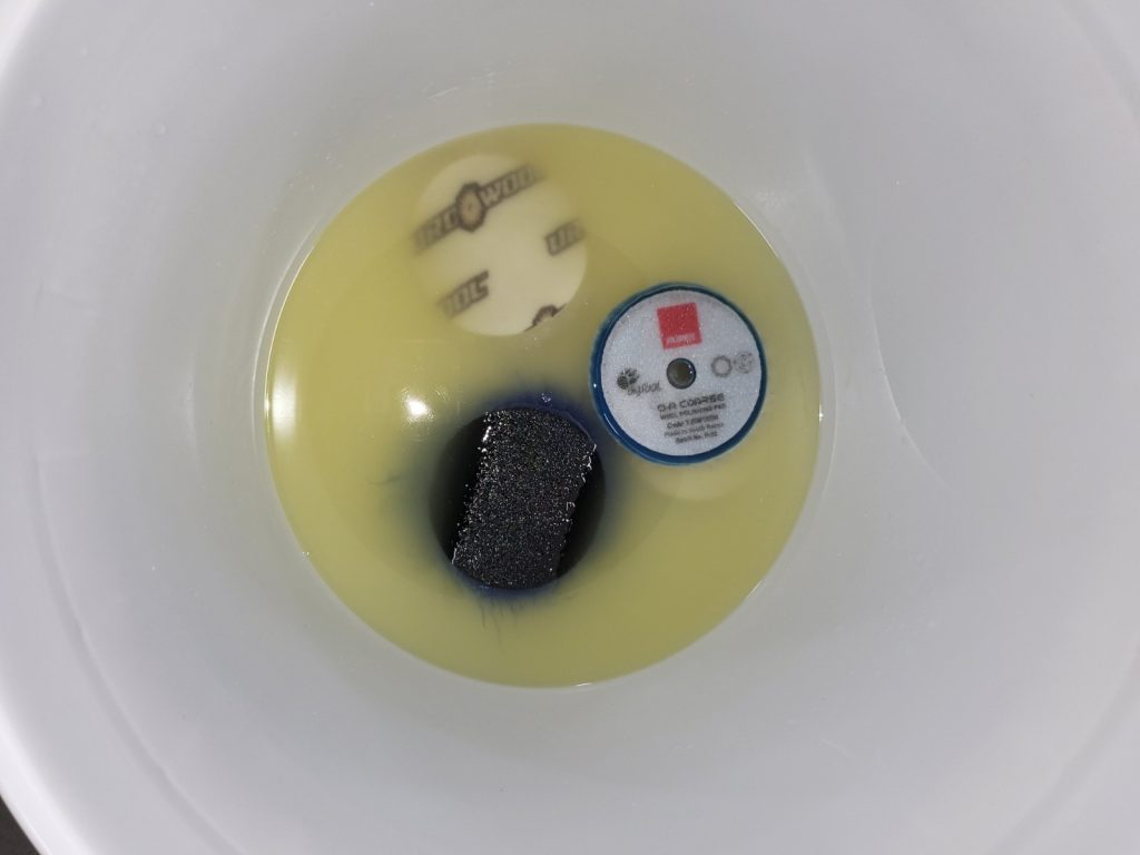 Pads laying face down in a bucket of pad cleaner